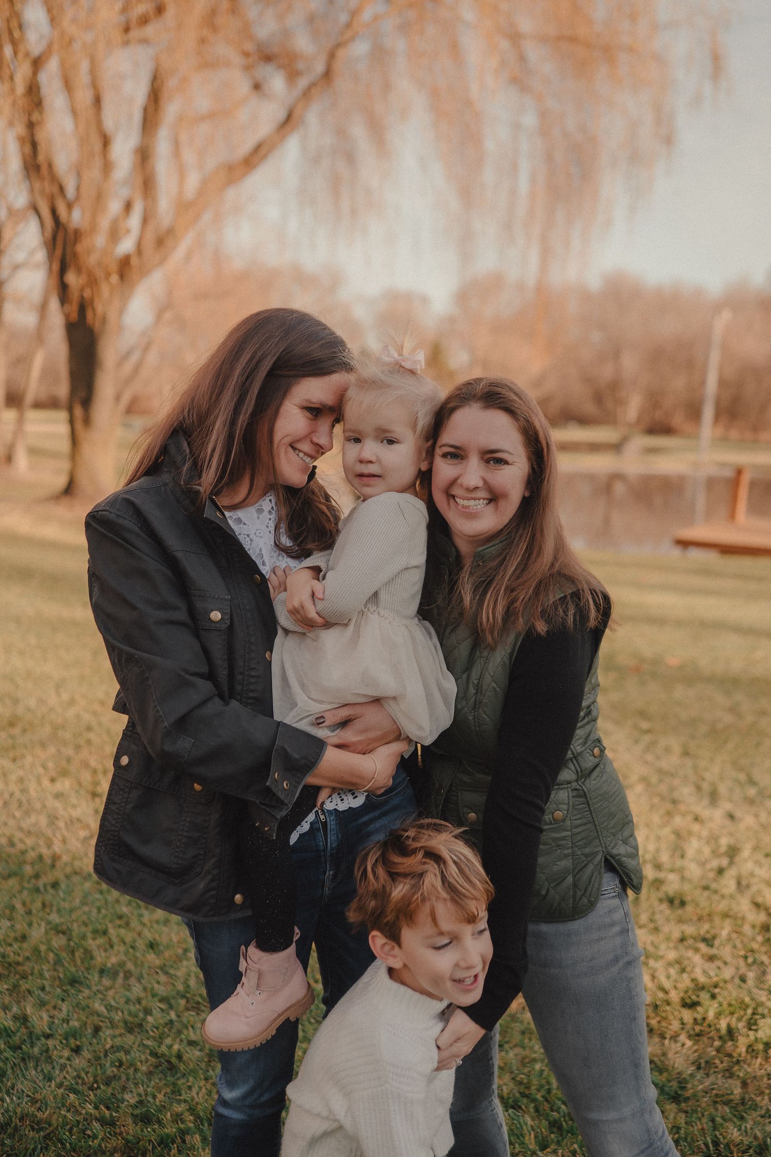 A playful family photo session in a park during autumn with everyone laughing and embracing.