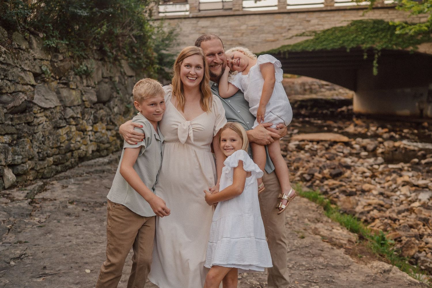 Family enjoying time together near a stone bridge and creek during an outdoor photo session.