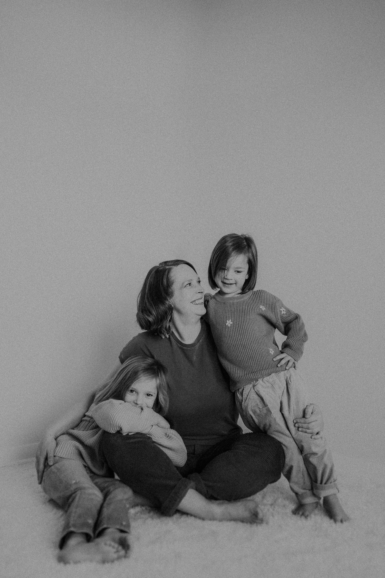 Intimate black and white family portrait with relaxed poses on light background.