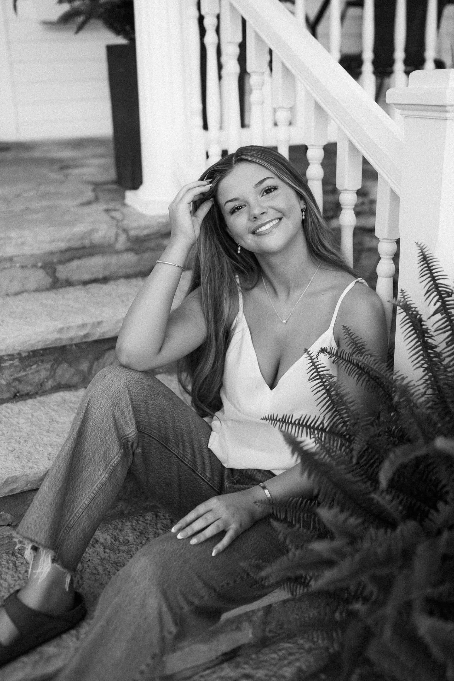 Casual black and white portrait on porch steps with white top and relaxed styling.