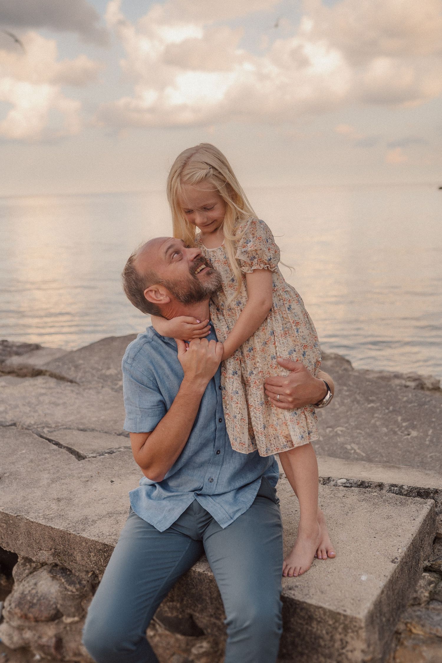 Four candid moments captured at sunset by the ocean shore showing playful interactions on rocky coastal terrain.