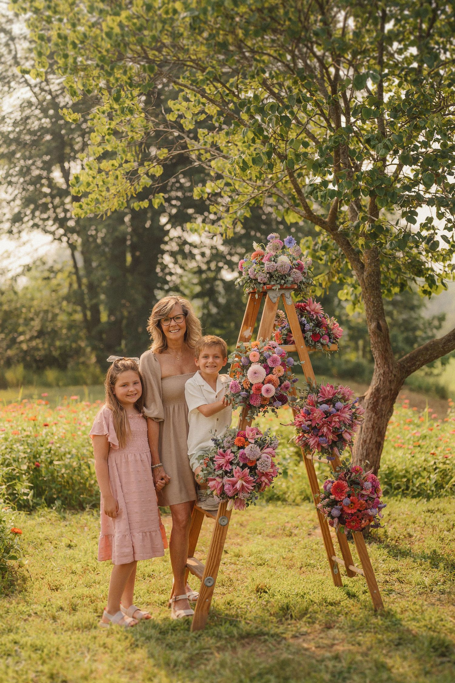 A four-panel sequence of outdoor family photos in a sunny garden setting with colorful pink and purple floral arrangements.