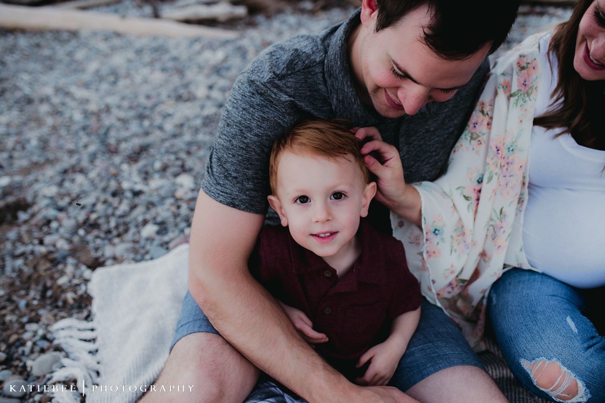 A candid family moment captured during a beach photoshoot with natural expressions.