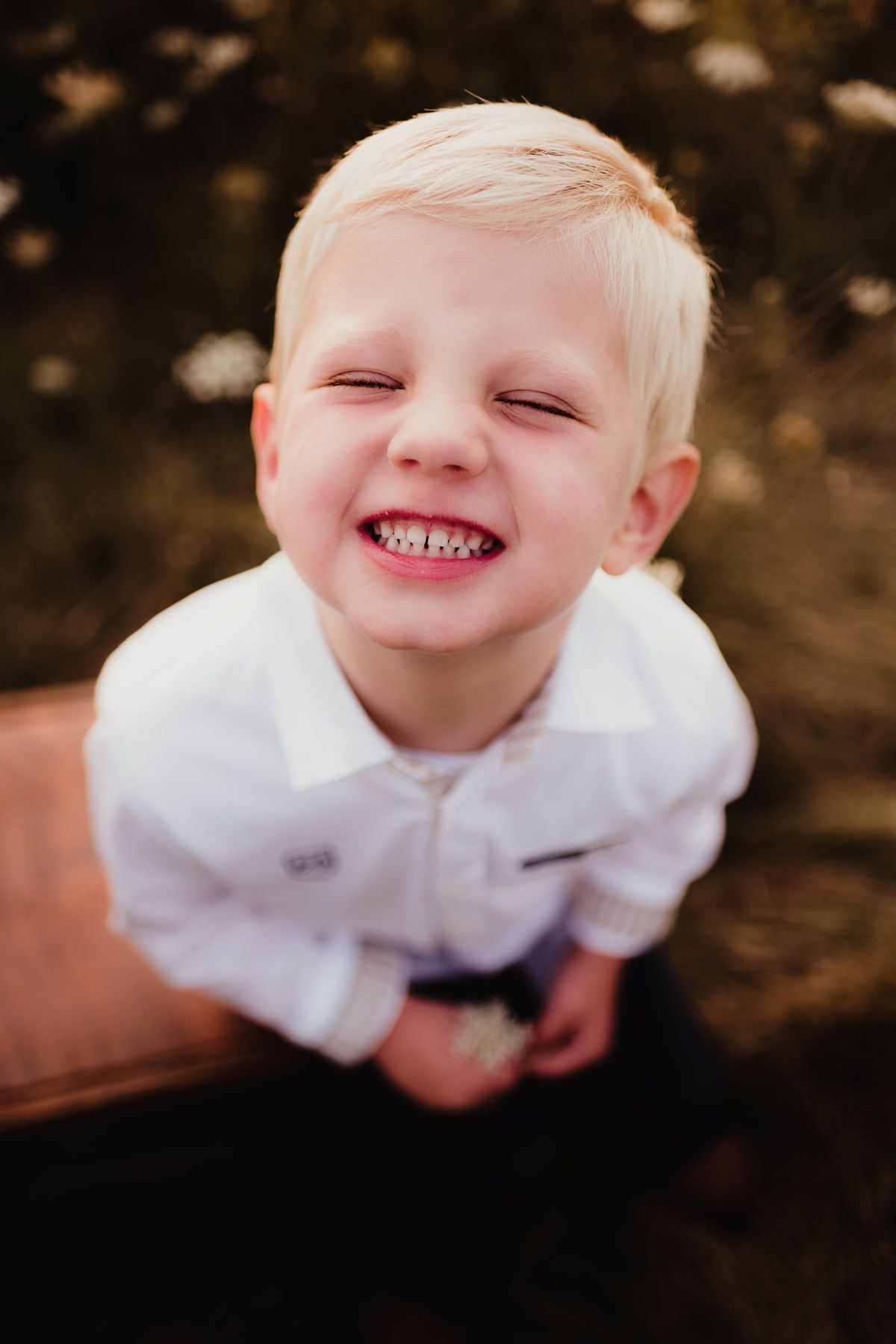 Close-up portrait of joyful young child in white shirt showing bright smile.