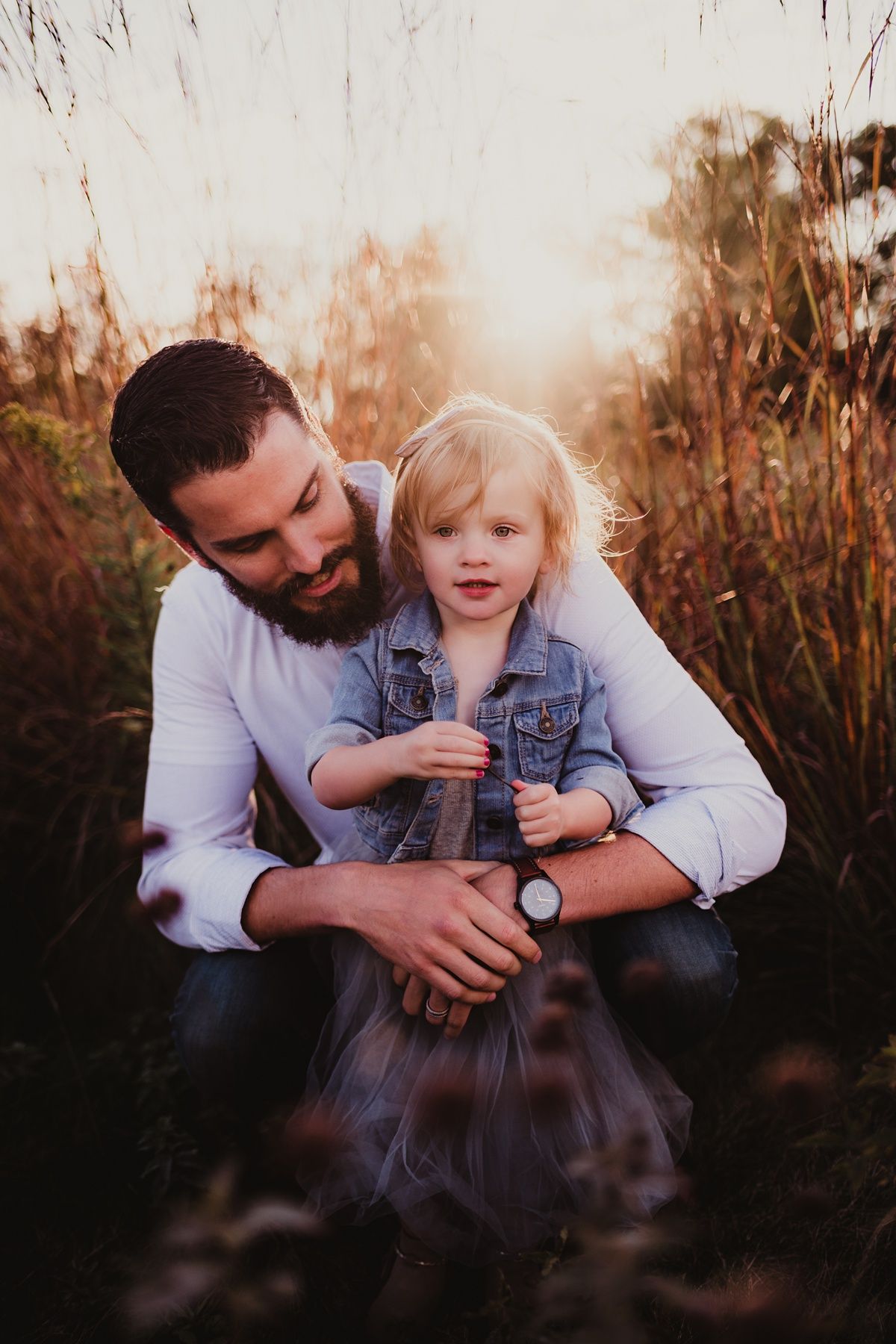 Heartwarming sunset portrait in a field of tall grass showing a sweet bonding moment.