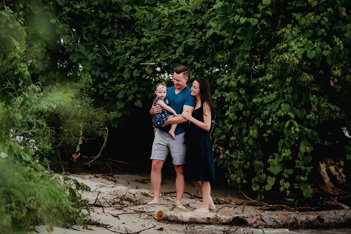 A family shares an intimate moment together on rocky terrain surrounded by lush greenery.