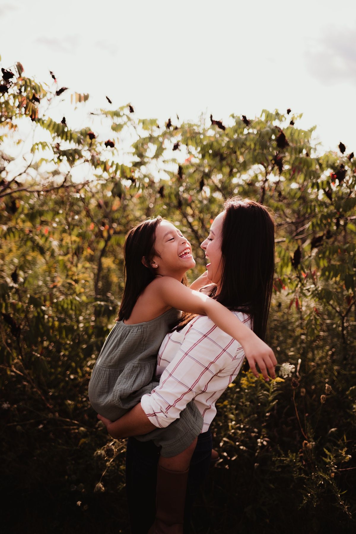 Joyful moment captured between two people laughing and embracing in a natural outdoor setting.