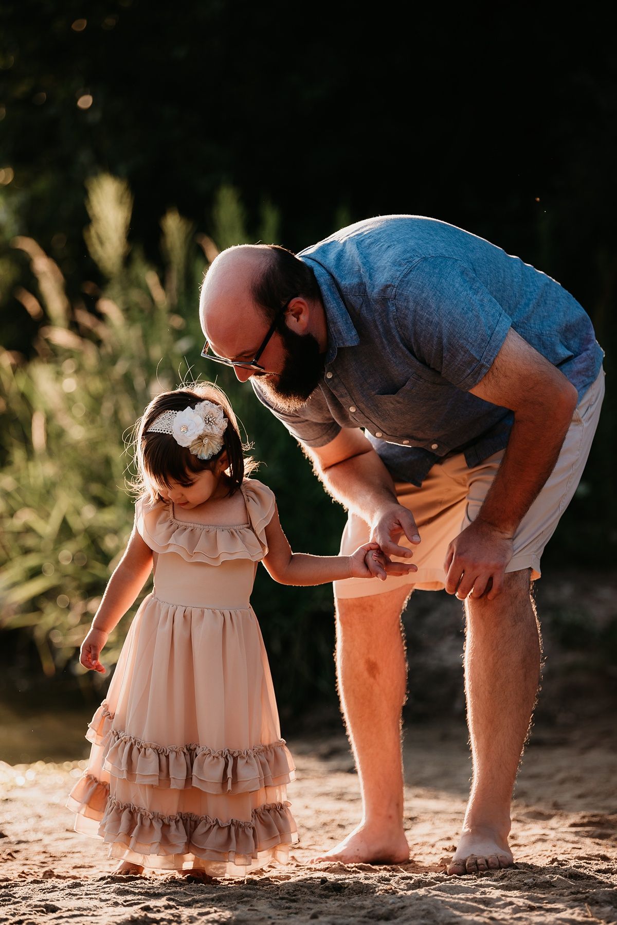 A heartwarming moment between two people in casual summer attire standing on sandy ground.