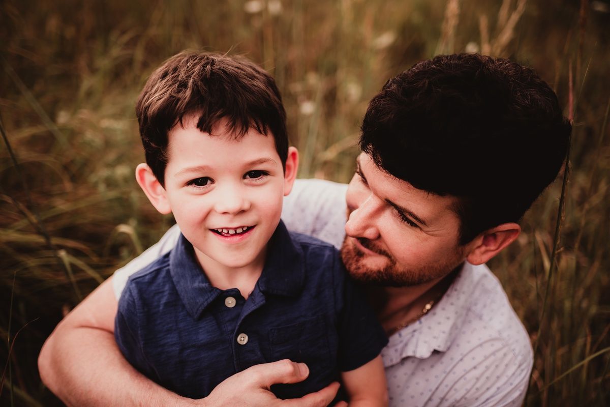 Heartwarming moment shared between parent and child in grassy field.