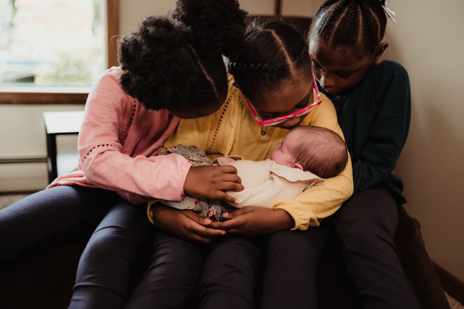 Caregivers tenderly holding and looking at a newborn baby while sitting together on a couch.