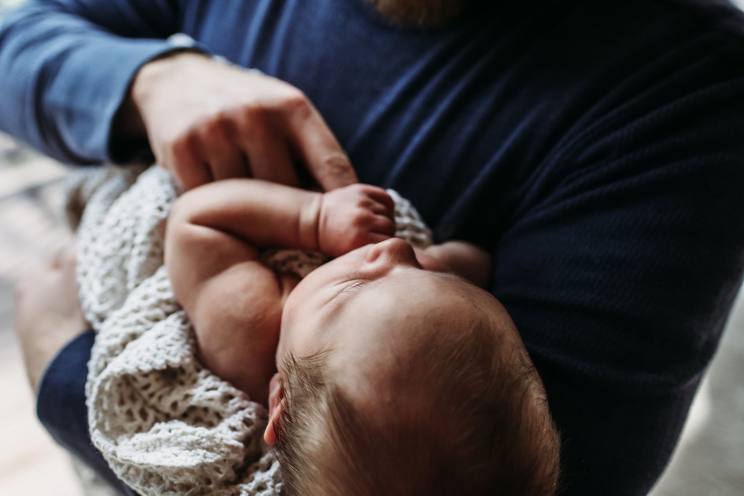 Close-up view of tiny hands and peaceful expression during newborn photoshoot.