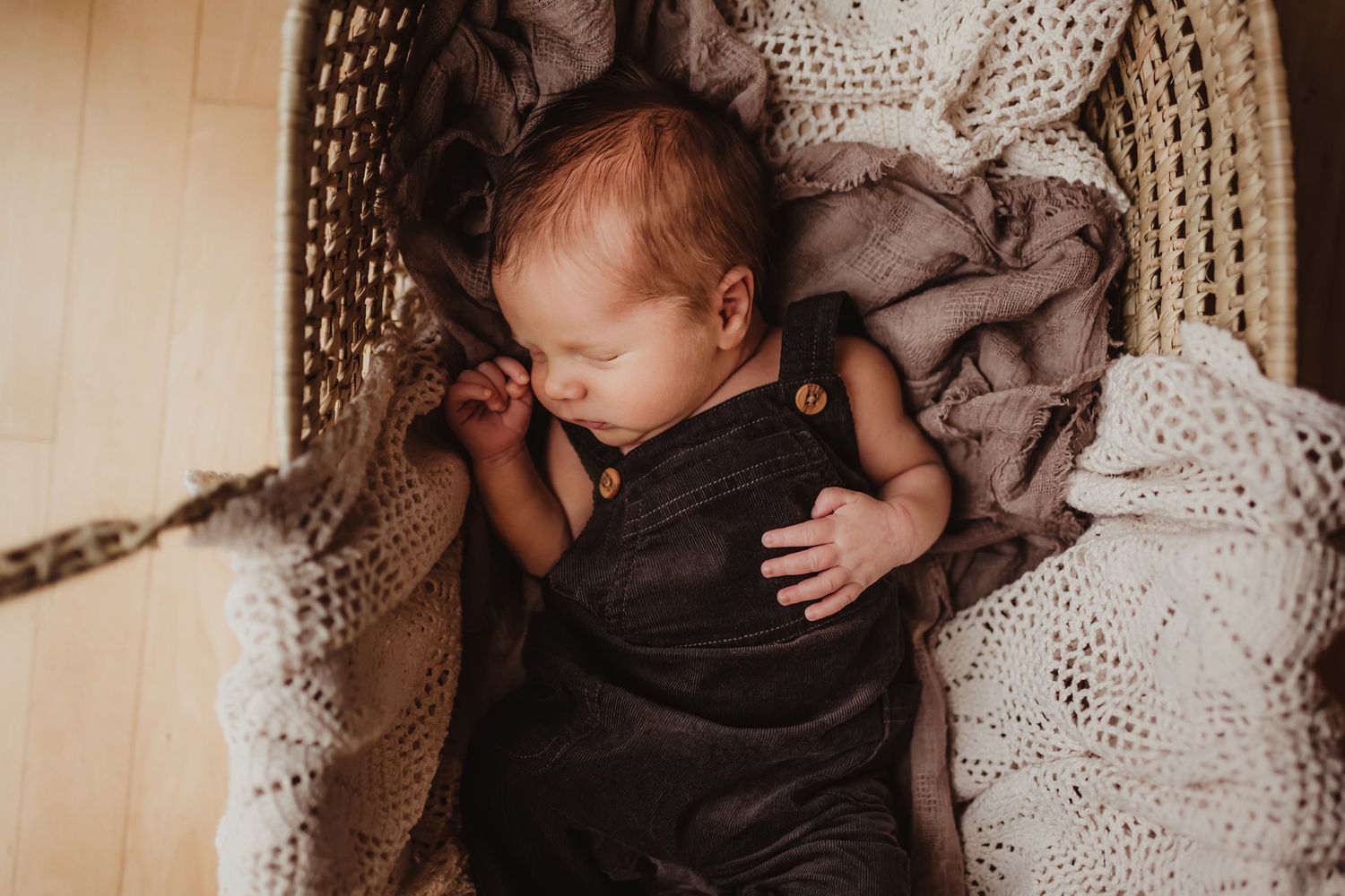 Sleeping infant nestled in cozy knit blankets and dark clothing.