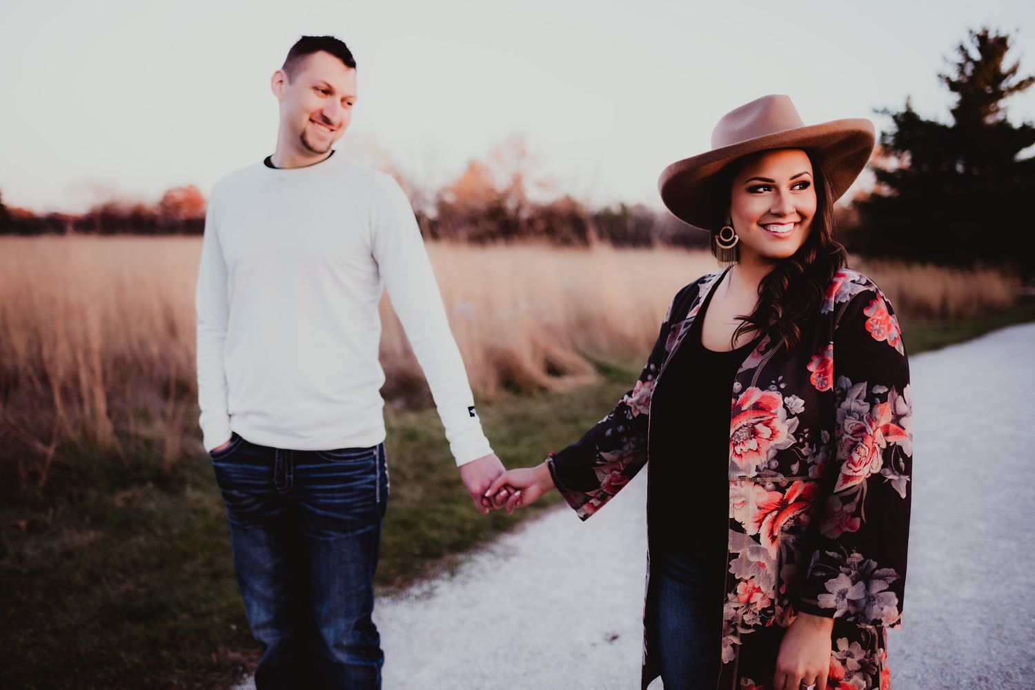 A joyful moment shared between a couple on a path surrounded by autumn grass.