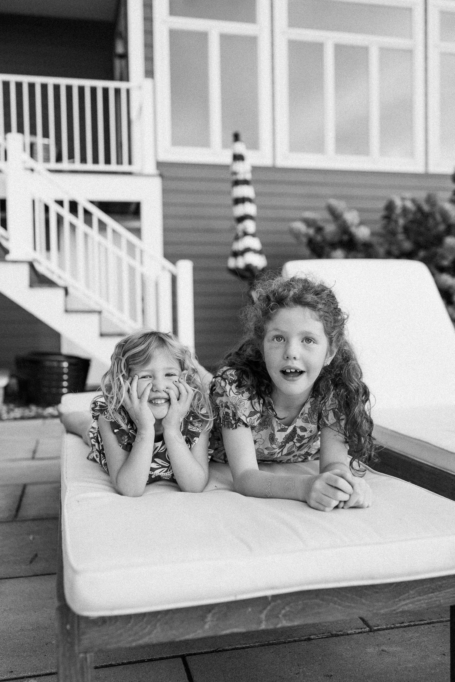 Children laying on their stomachs on a white surface making playful expressions.