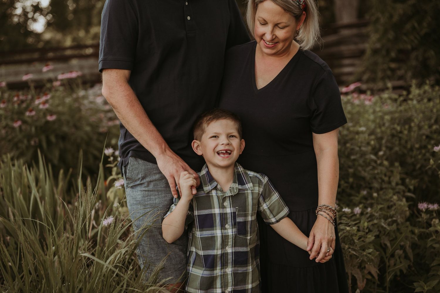 Candid family moment in garden setting with laughing child between parents.