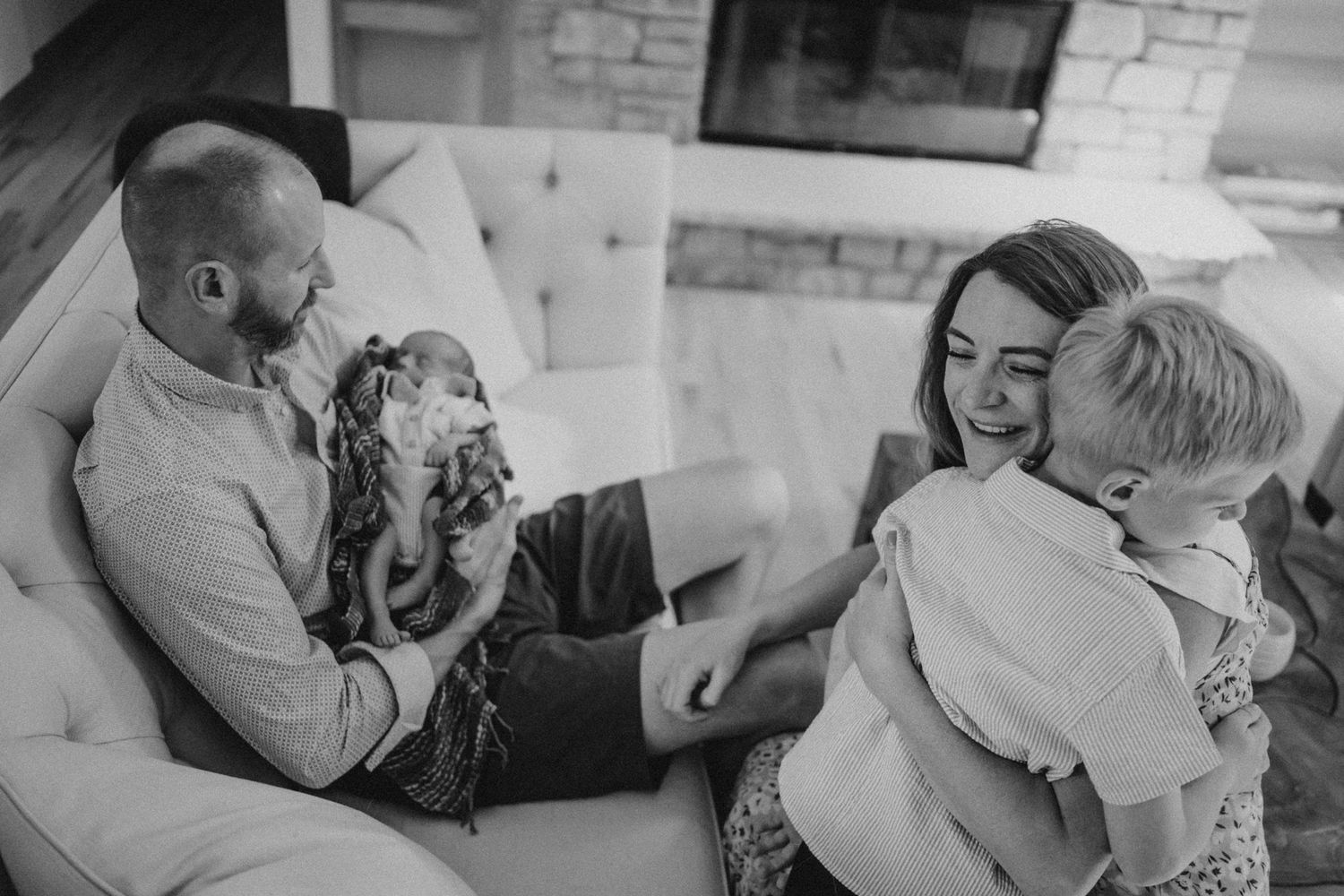 Black and white portrait capturing sweet family interactions on white sofa.