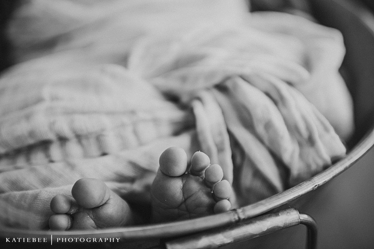 Close-up black and white photo of tiny baby feet on textured blanket.