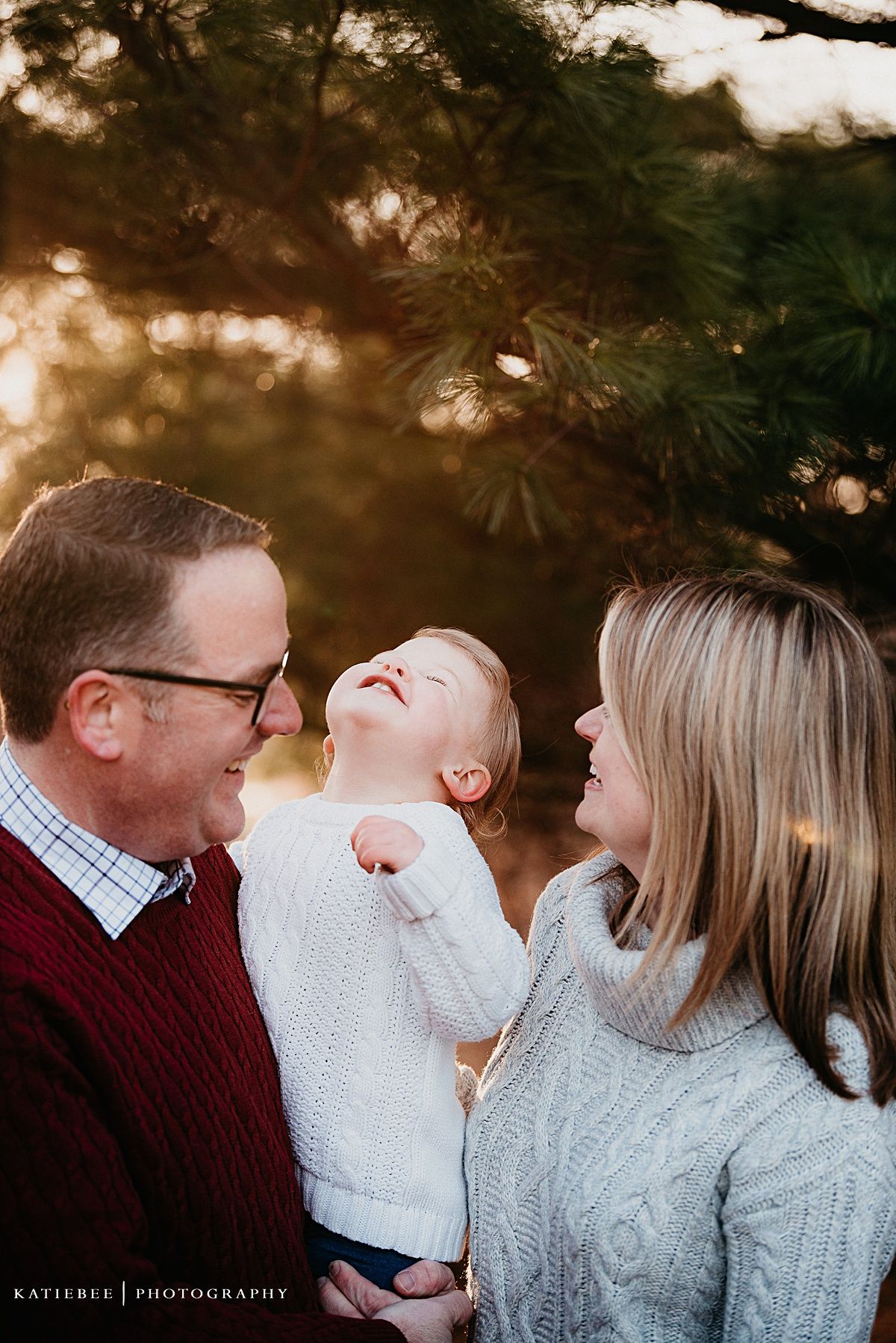 A candid family portrait showing genuine laughter and joy during sunset in nature.