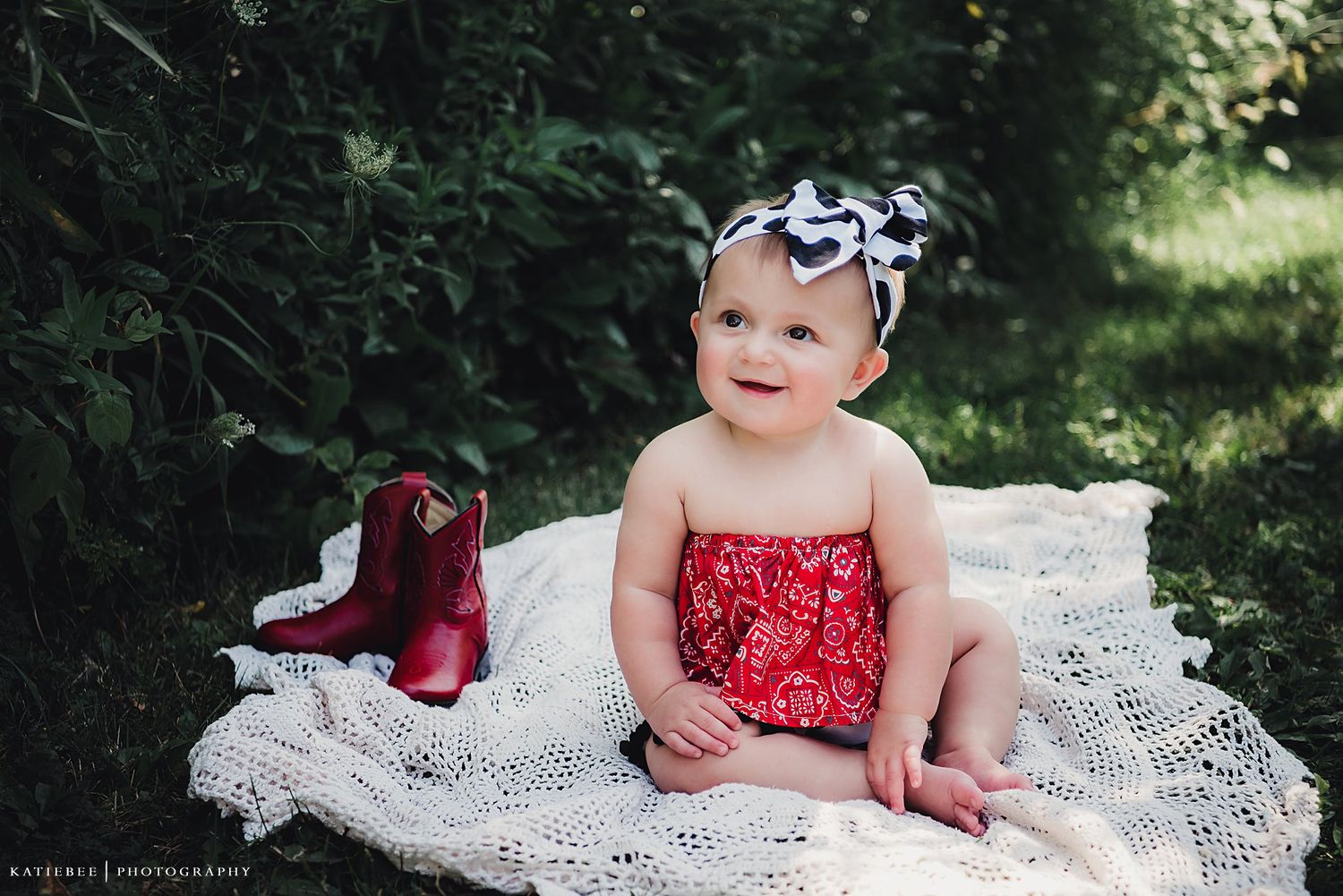 Red dress and bow against white lace blanket in garden setting.