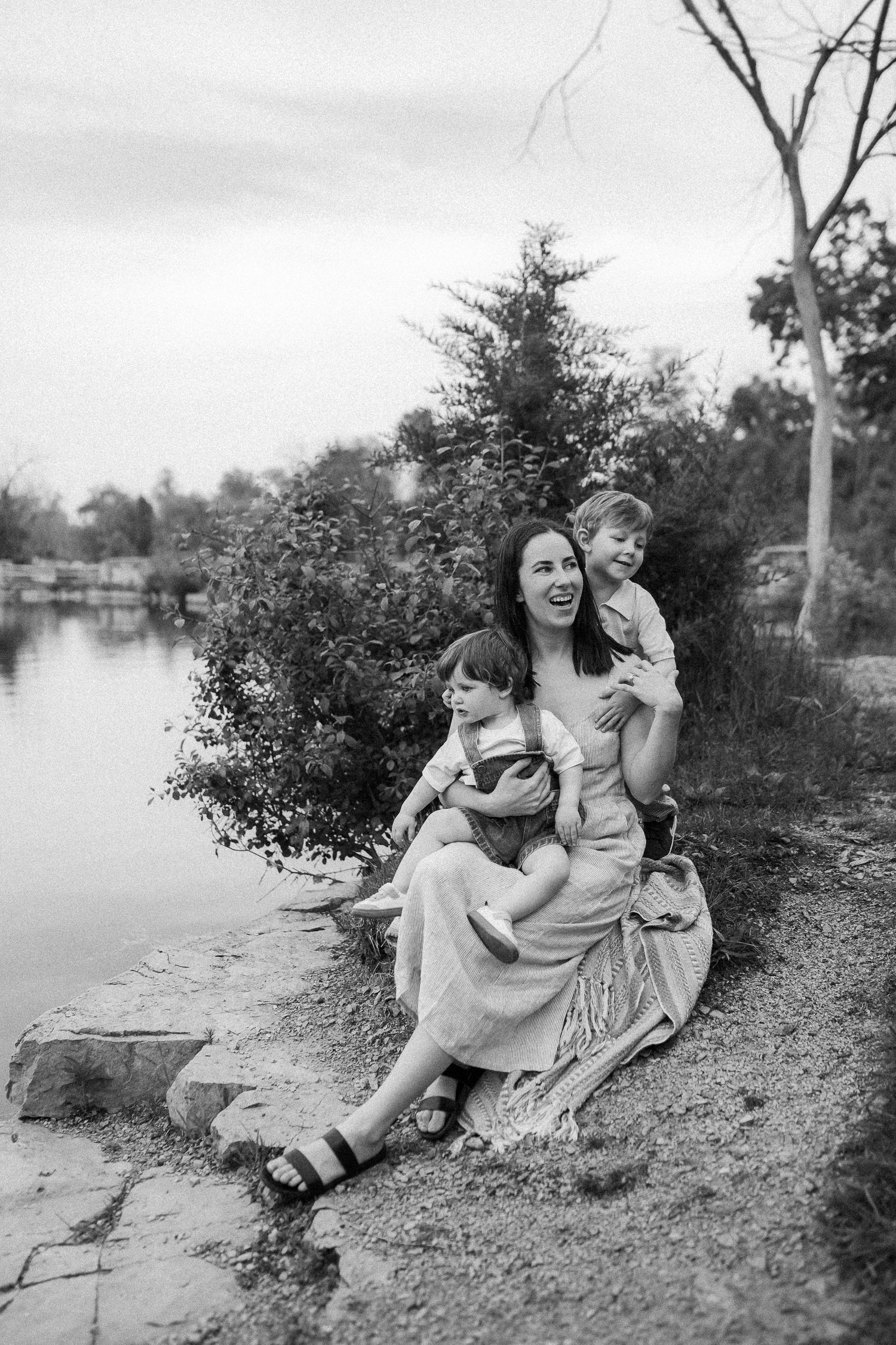 Black and white portrait by a serene lake showing affectionate moments amidst nature.