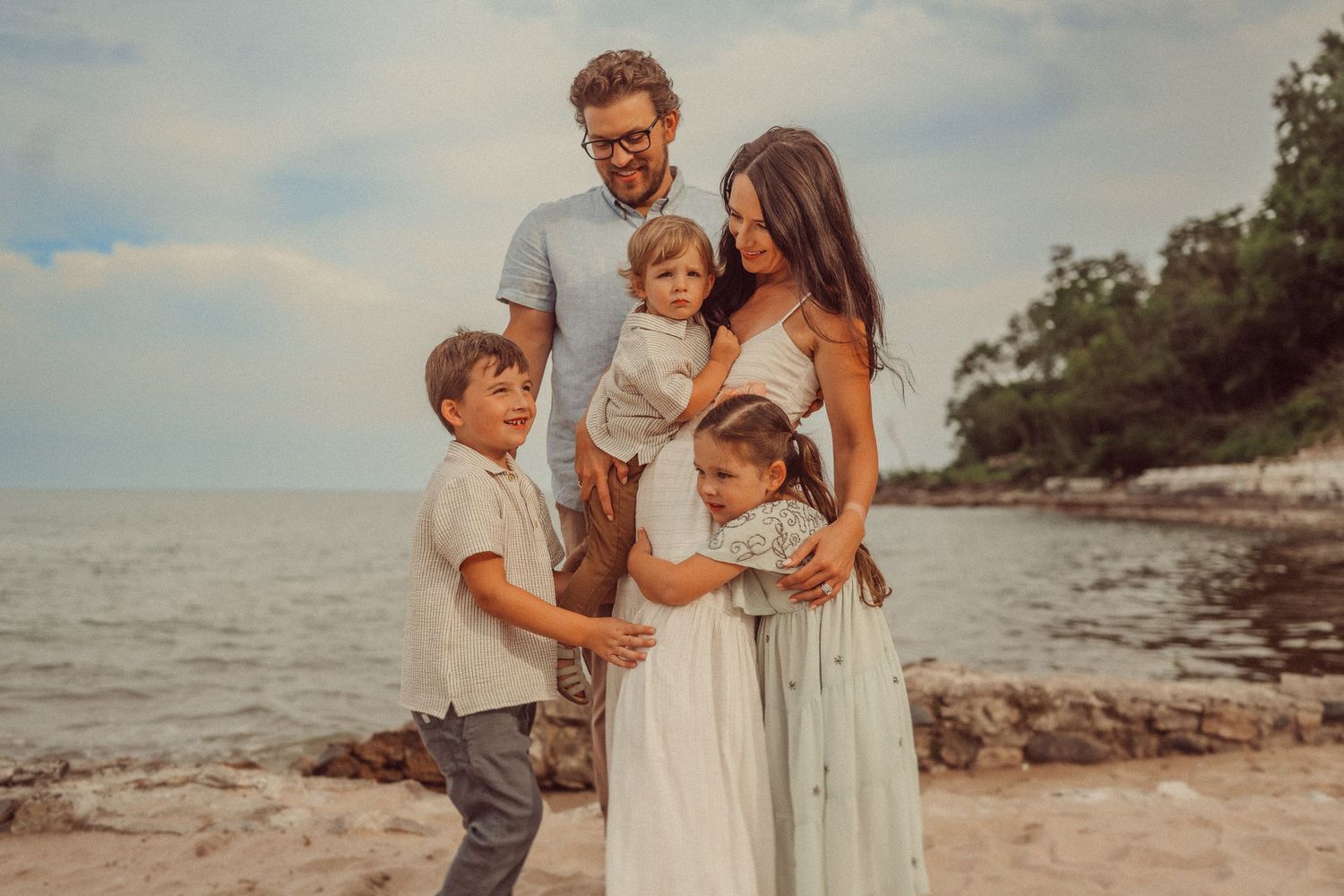 A family holds each other close during their beach portrait session at sunset.