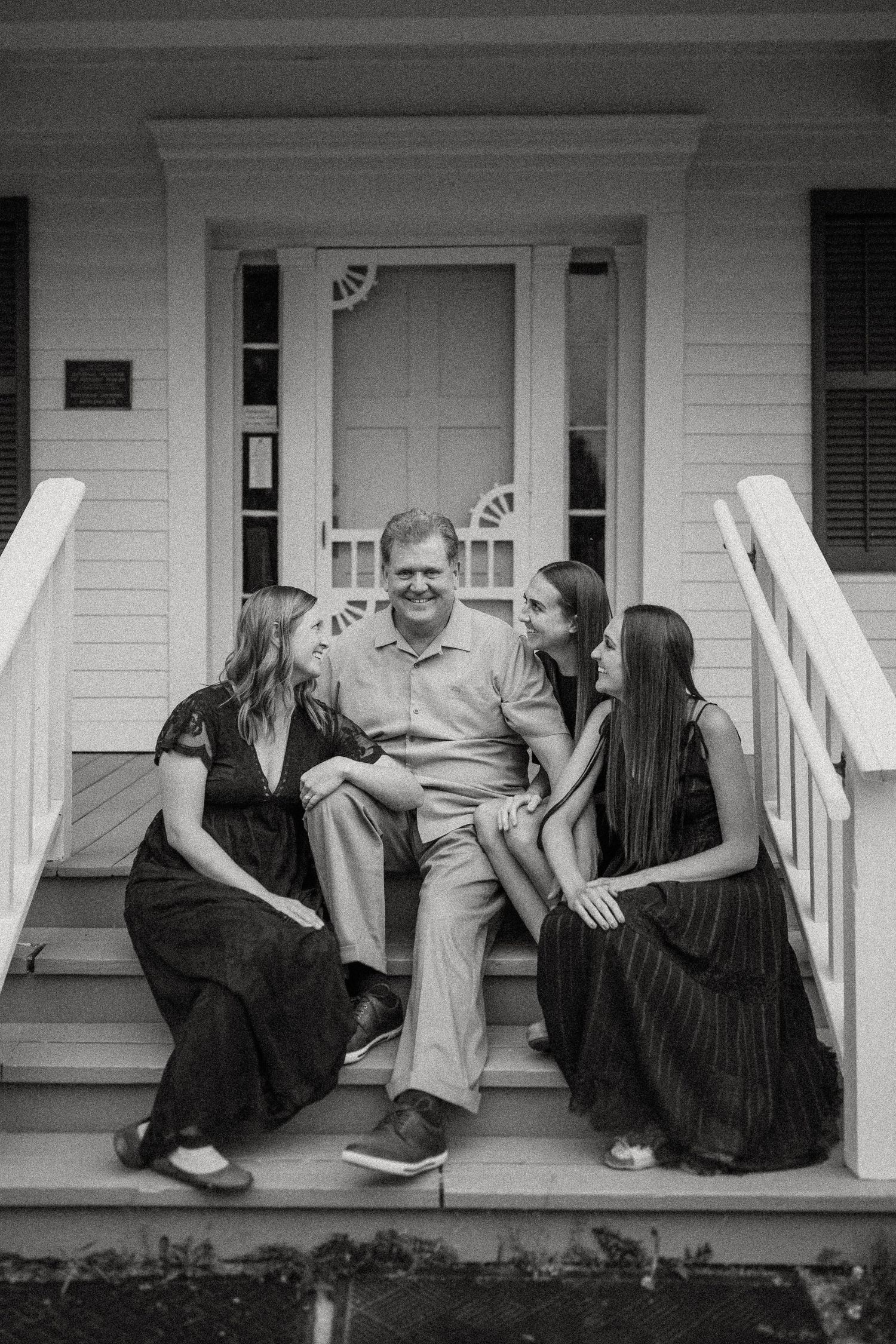 Intimate family portrait on white porch steps in black and white photography.