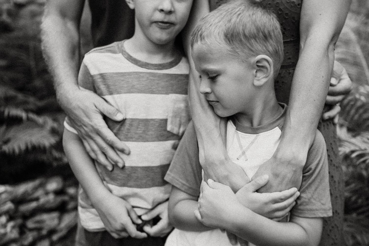 Close-up black and white shot showing hands comforting a young child.