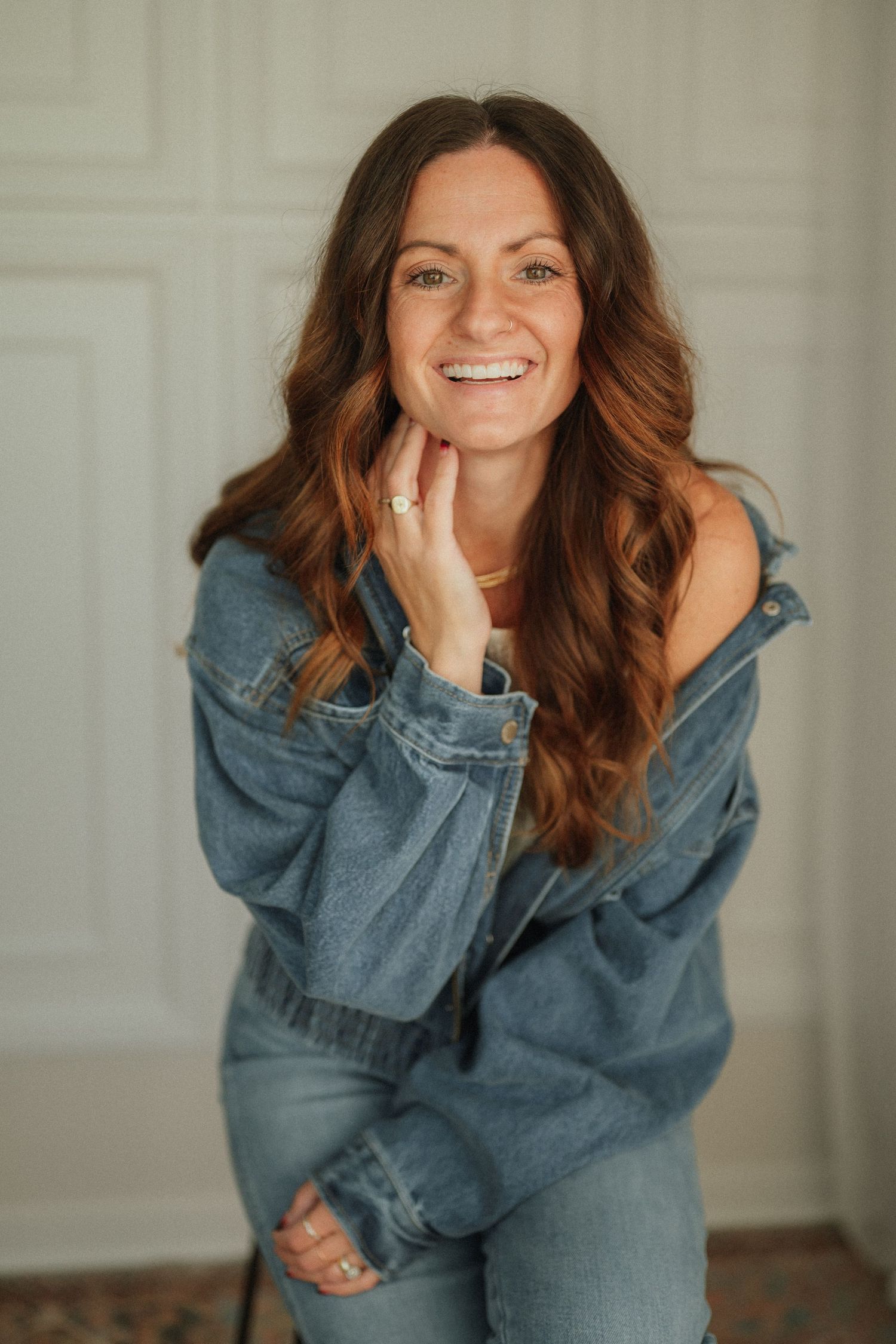 Indoor portrait series showing casual poses in an oversized denim jacket against a white wall.
