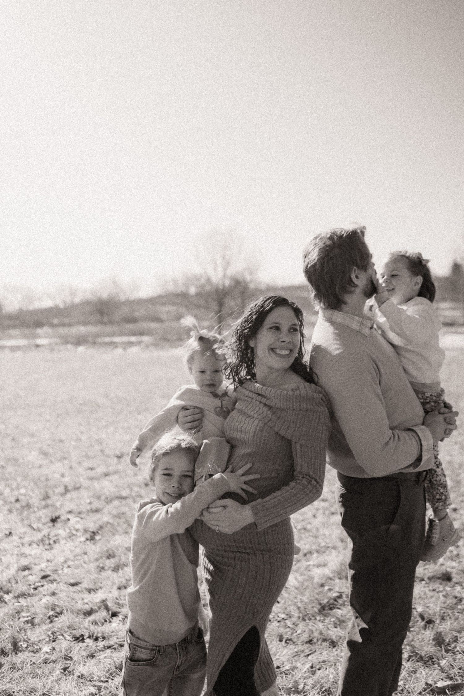 A tender family moment captured in black and white as they embrace in an open field.