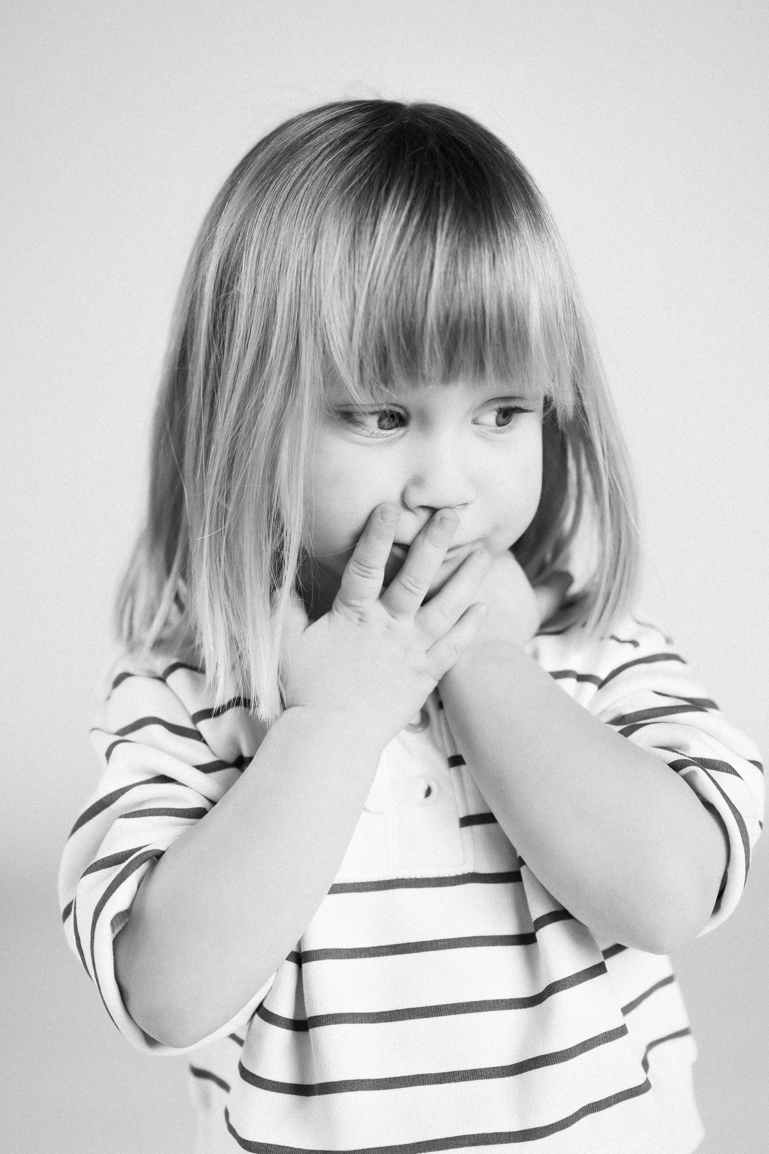 Black and white sequence of a child covering their face with hands while wearing a striped shirt.