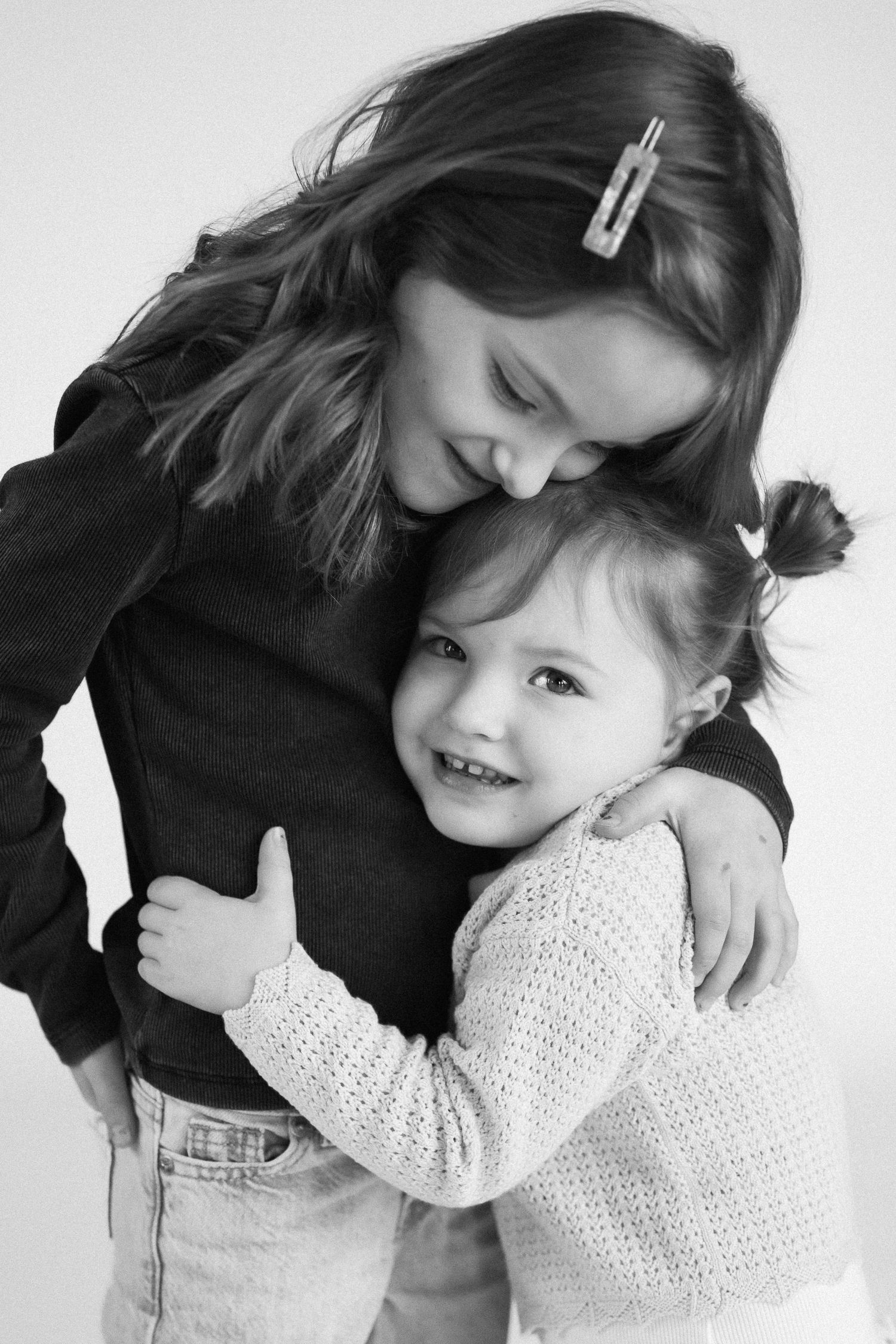 Sweet monochrome sequence capturing loving hugs and cuddles between family members against white backdrop.