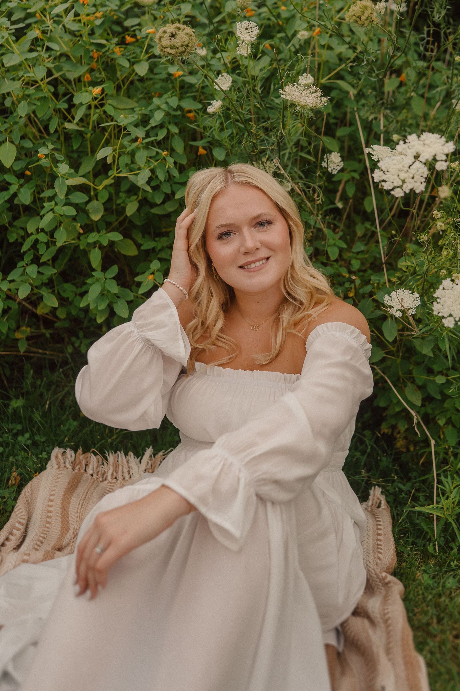 A romantic portrait session featuring a white dress against lush greenery and florals in a garden setting.
