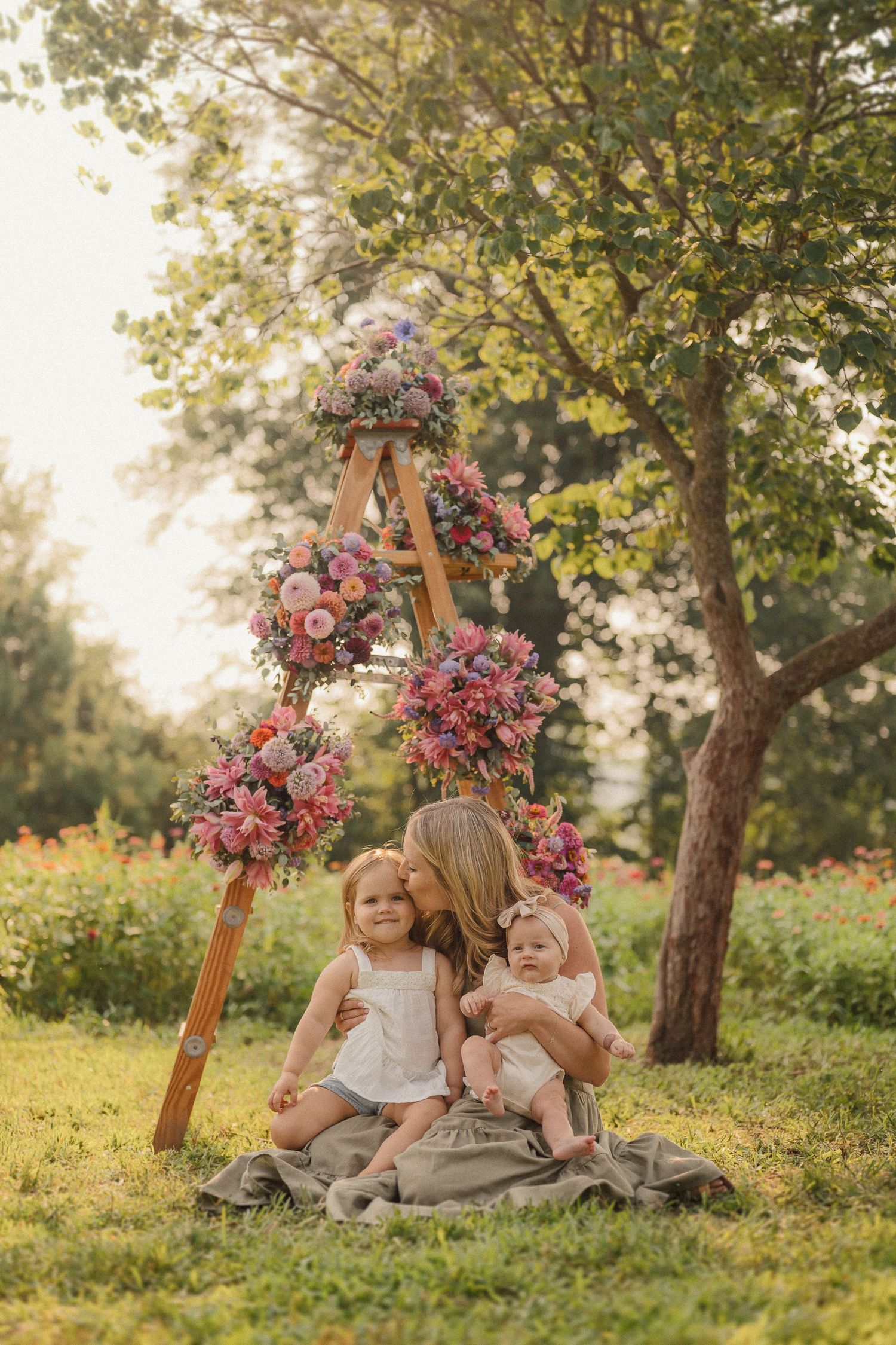 Sweet family portrait session in a garden setting with wooden arch decorated in pink and purple flowers.