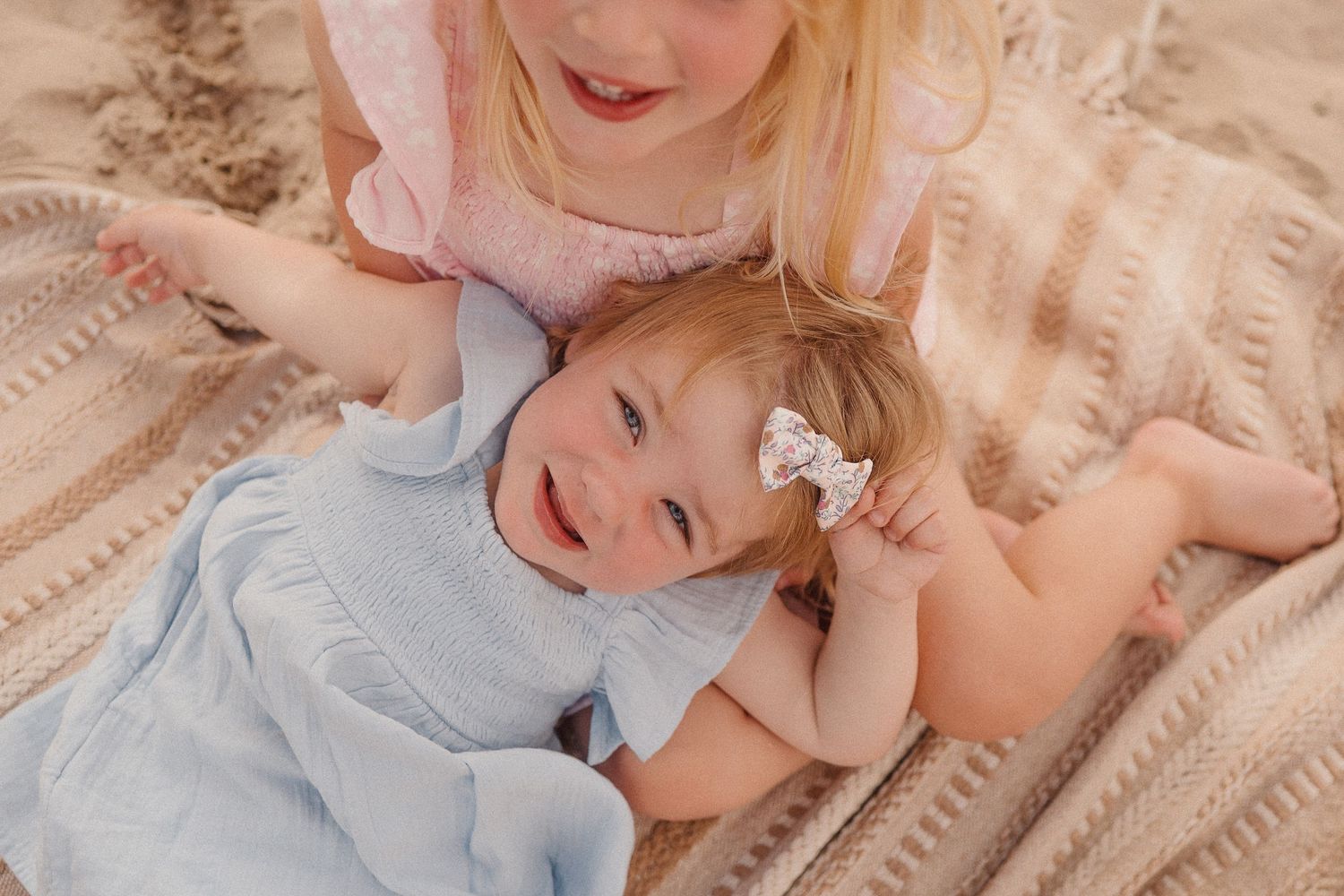A baby lying on a blanket outdoors with joyful expression.