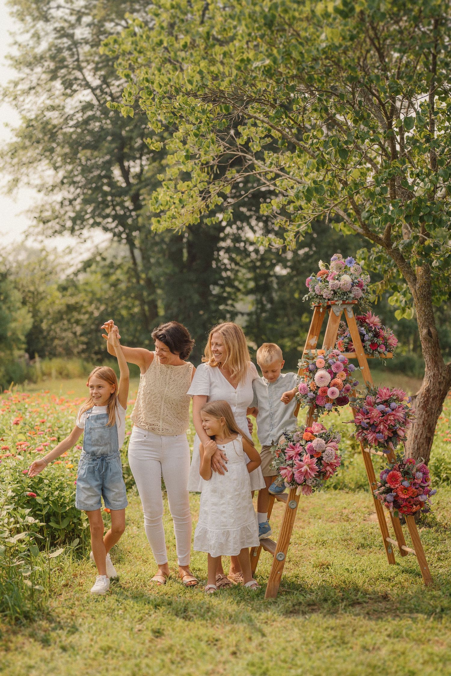 A joyful family moment captured in a sunny outdoor setting with colorful floral arrangements and natural greenery.