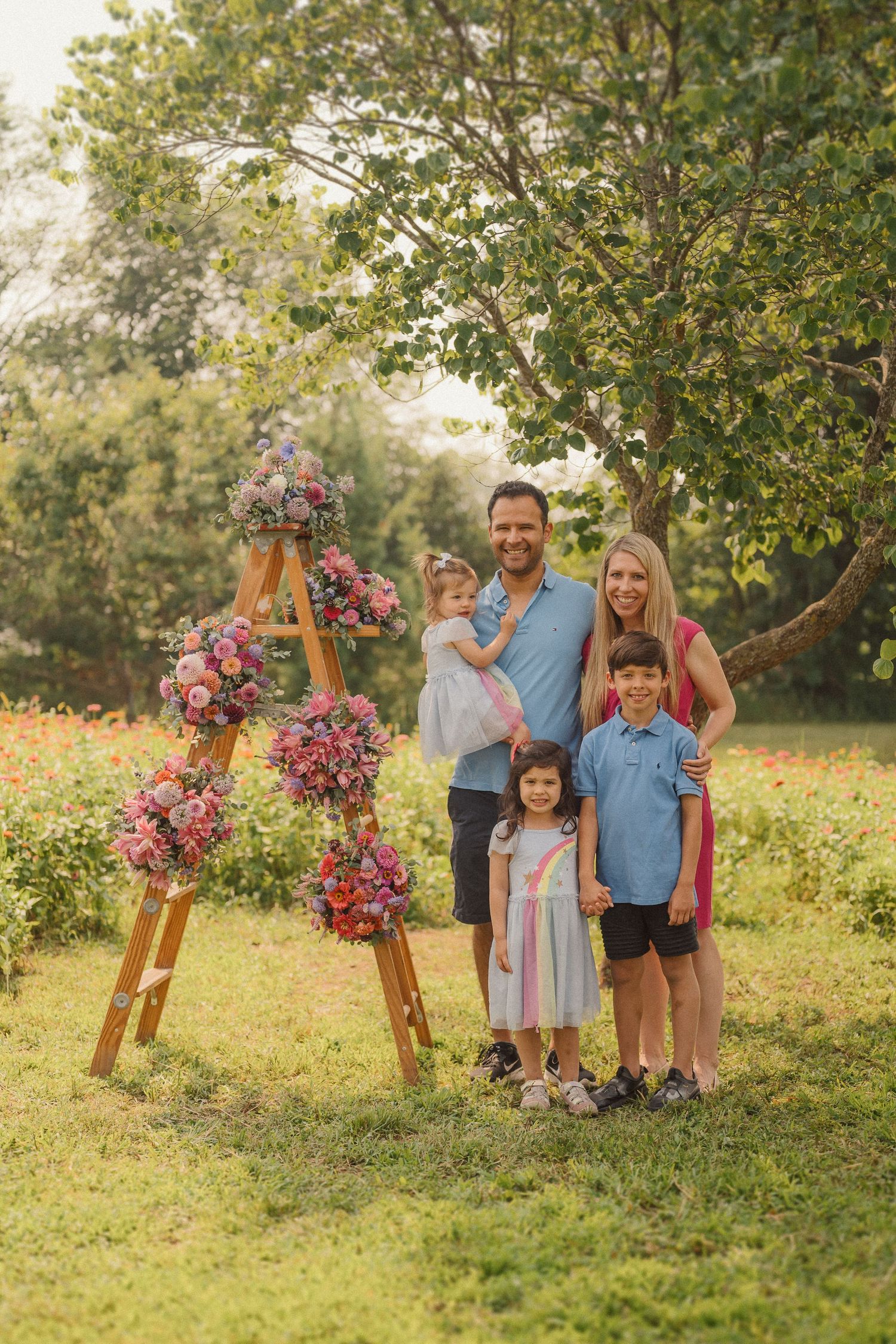 Outdoor family photoshoot setup featuring a wooden ladder adorned with beautiful pink and purple floral arrangements.