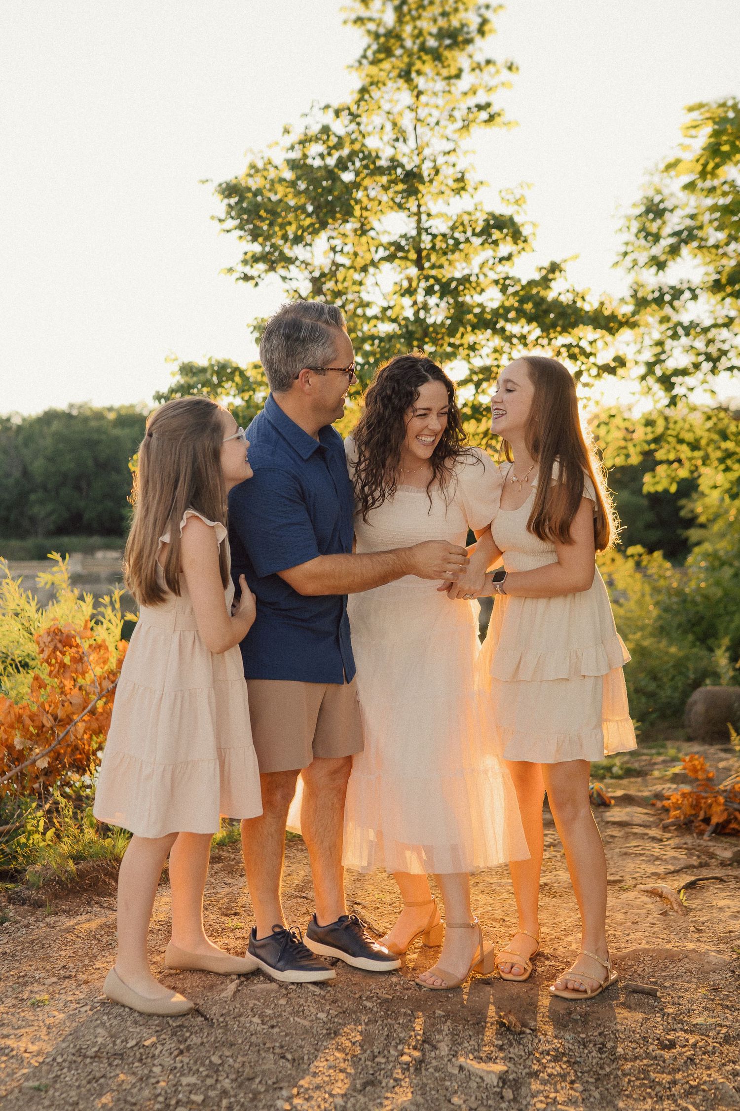 A family shares a joyful moment together outdoors during sunset with autumn foliage behind them.