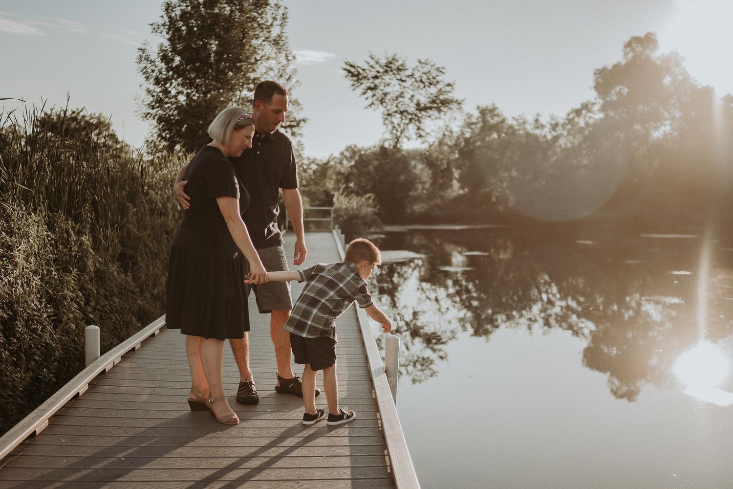 Family standing together on a wooden dock during golden hour.