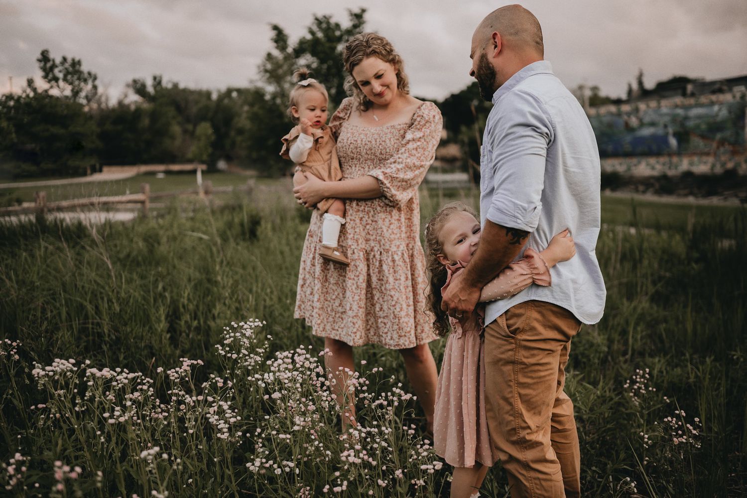 A family stands together in a field of wildflowers during golden hour.