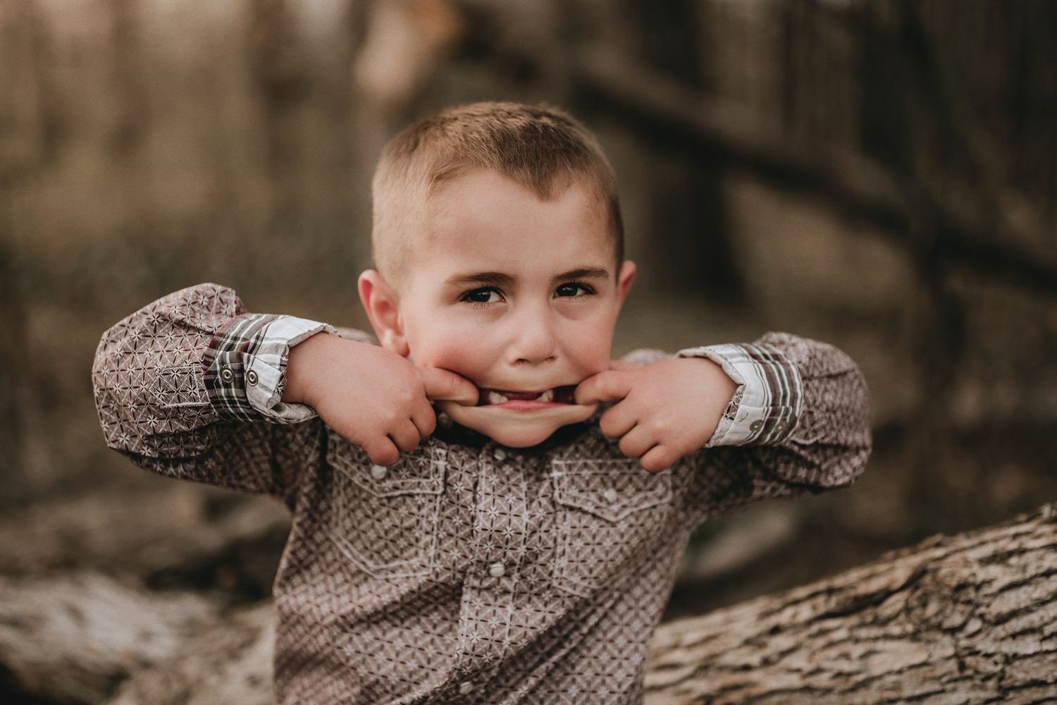 Young child in sweater making silly expression while playing outdoors.