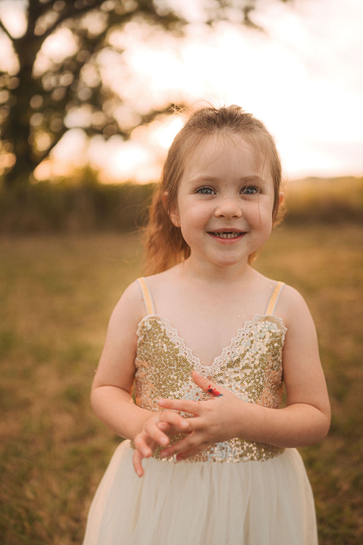 A joyful moment captured in golden light as a small figure wears a sparkly dress outdoors.