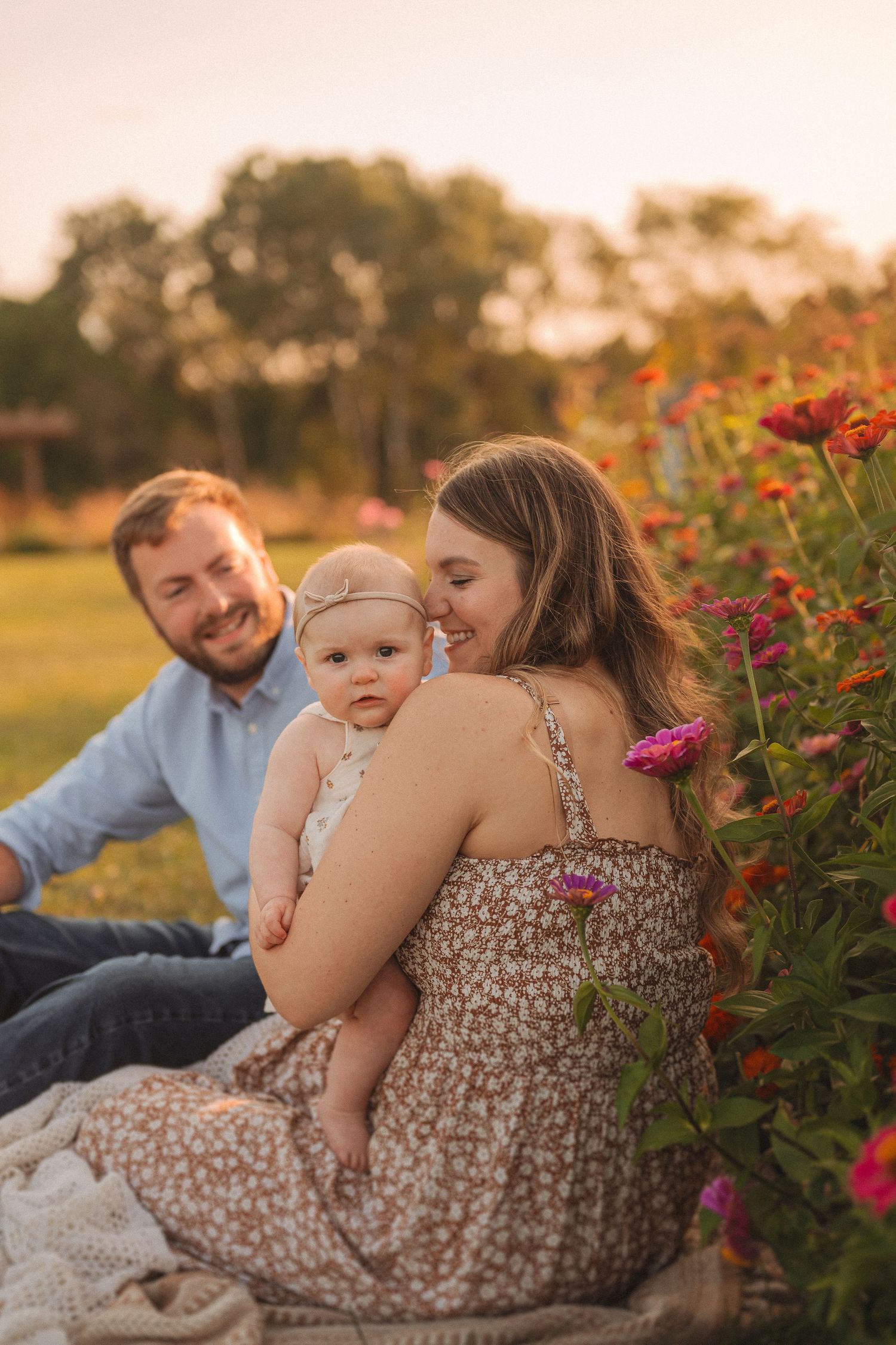Family sits together by blooming flowers during sunset in a garden setting.