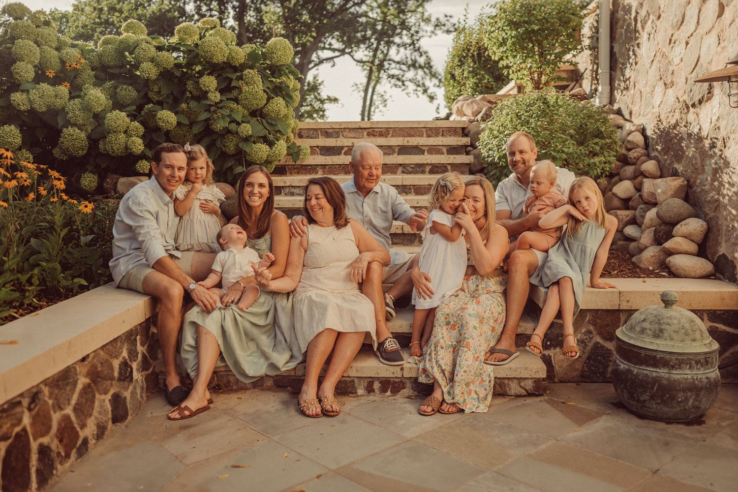 Sepia-toned portrait of a family gathered on stone garden steps with decorative planters.