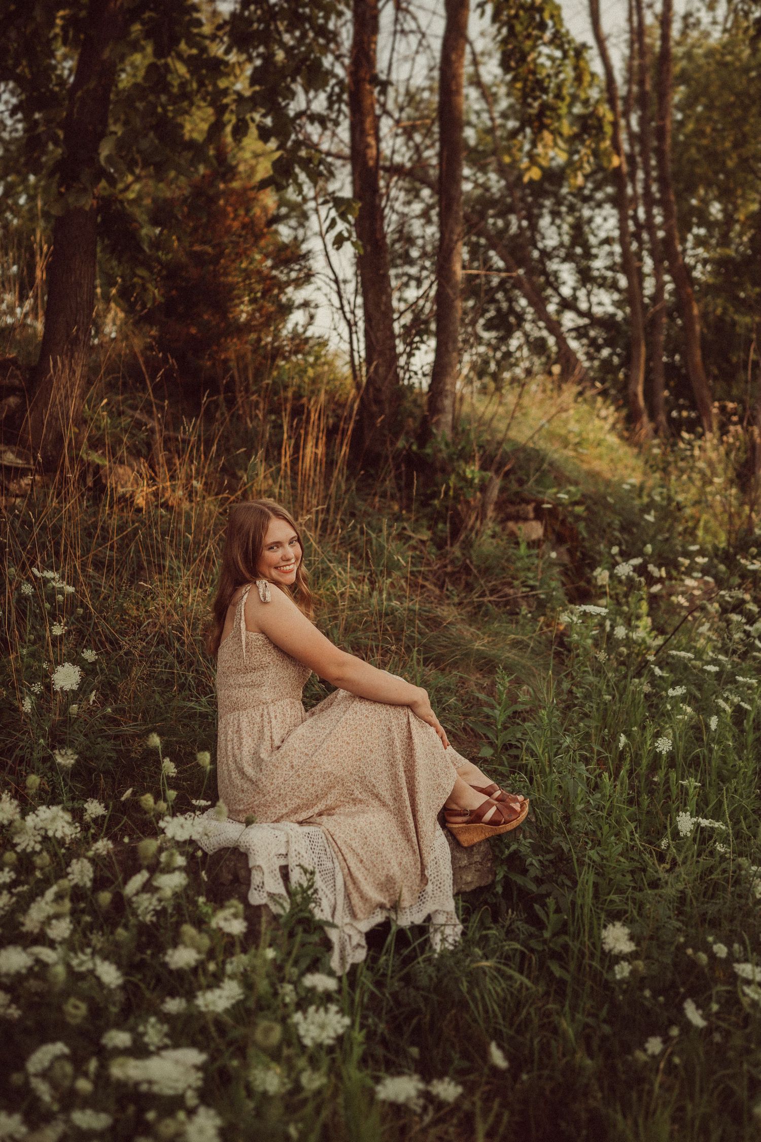 A whimsical garden portrait with golden hour lighting and white wildflowers in a forest setting.