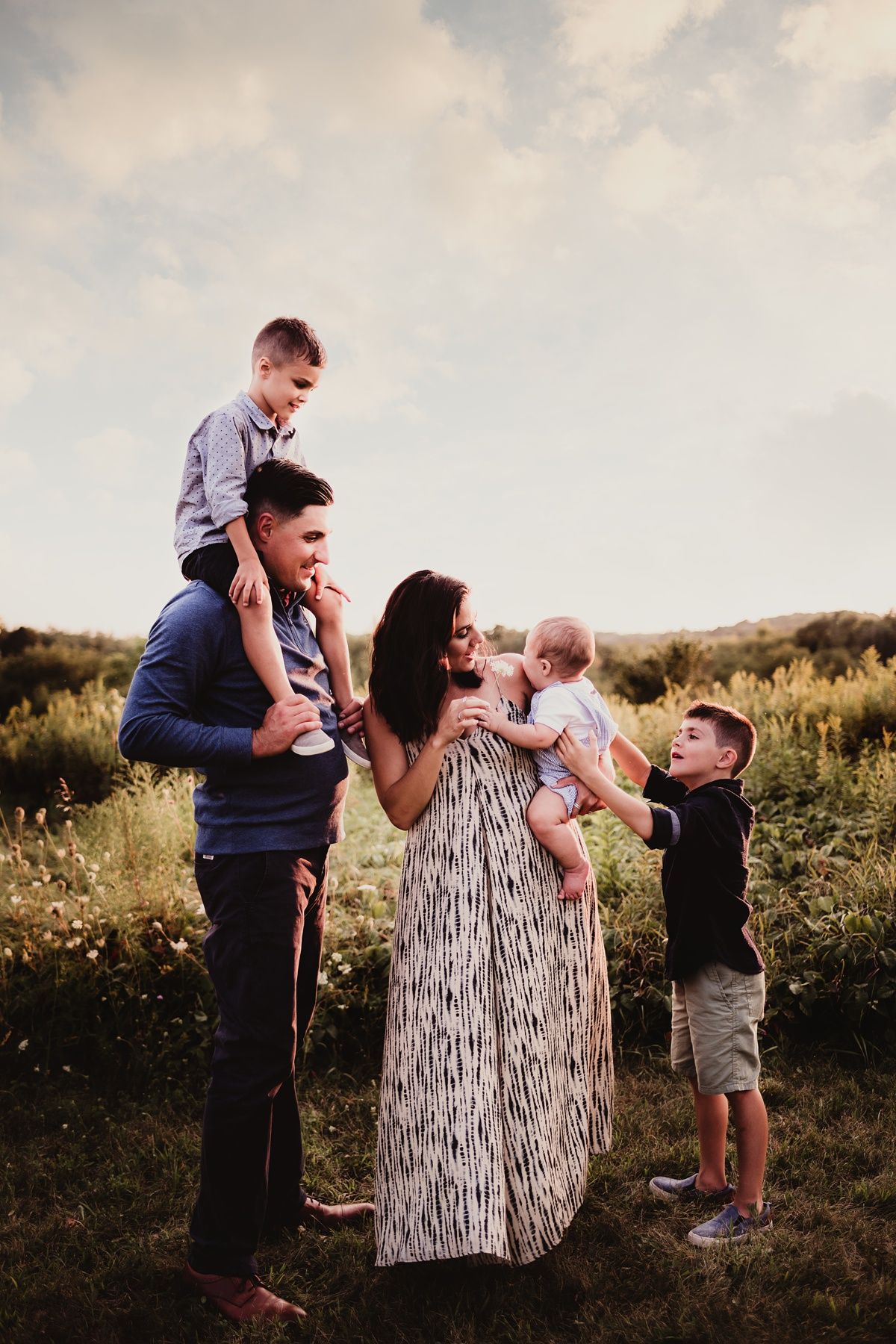 Family playing together outdoors during sunset photo session.