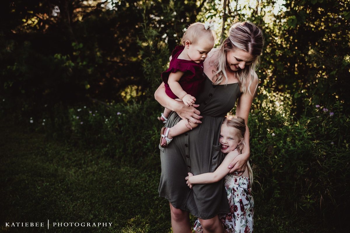 Candid family moment captured against lush greenery in natural light.
