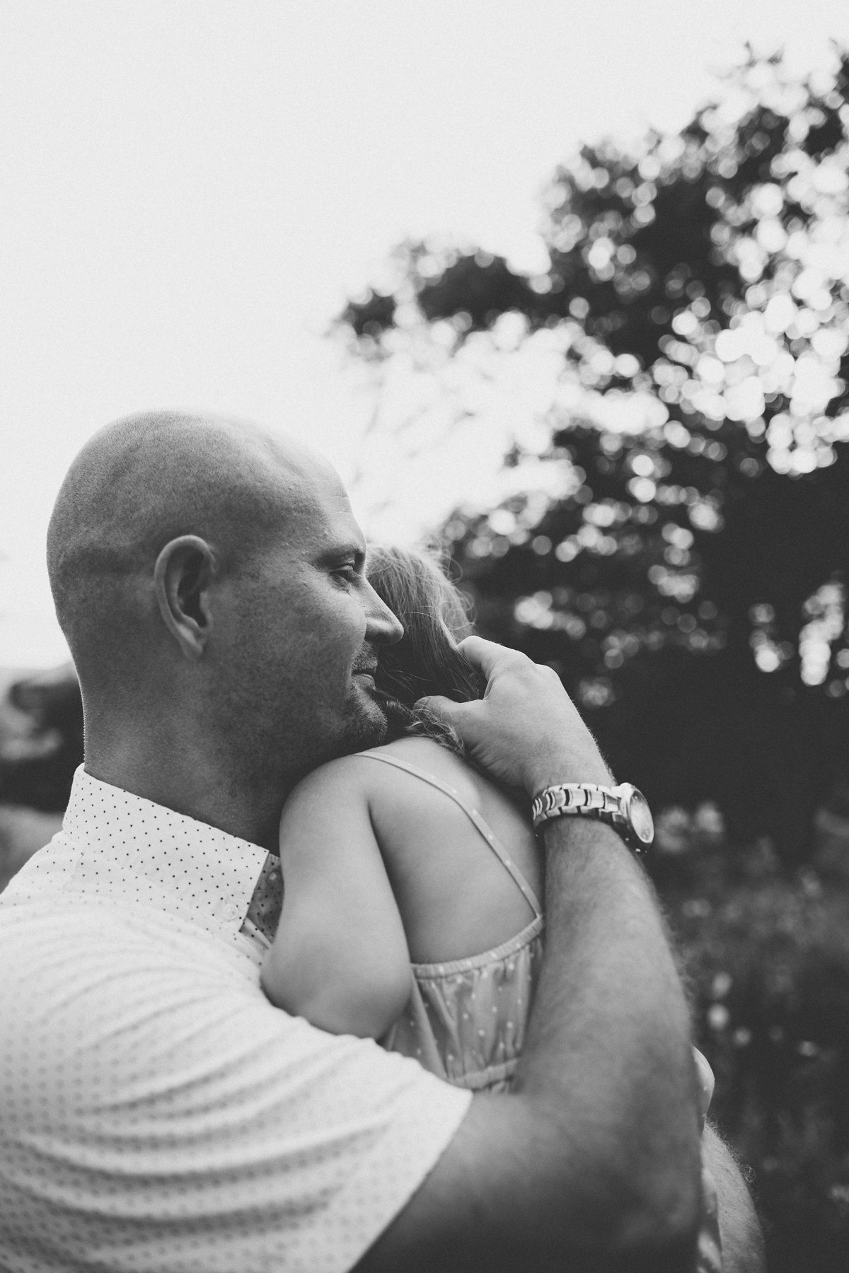 Black and white portrait showing gentle embrace in outdoor setting.