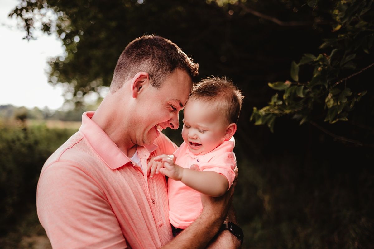 Intimate family portrait captured in warm sunset lighting against natural outdoor backdrop.