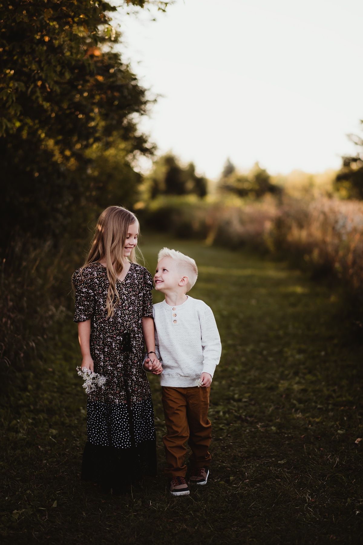 Two people sharing a joyful moment together outdoors with wildflowers at sunset.