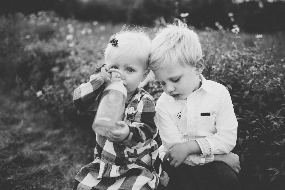 Black and white portrait of two children sitting together outdoors.